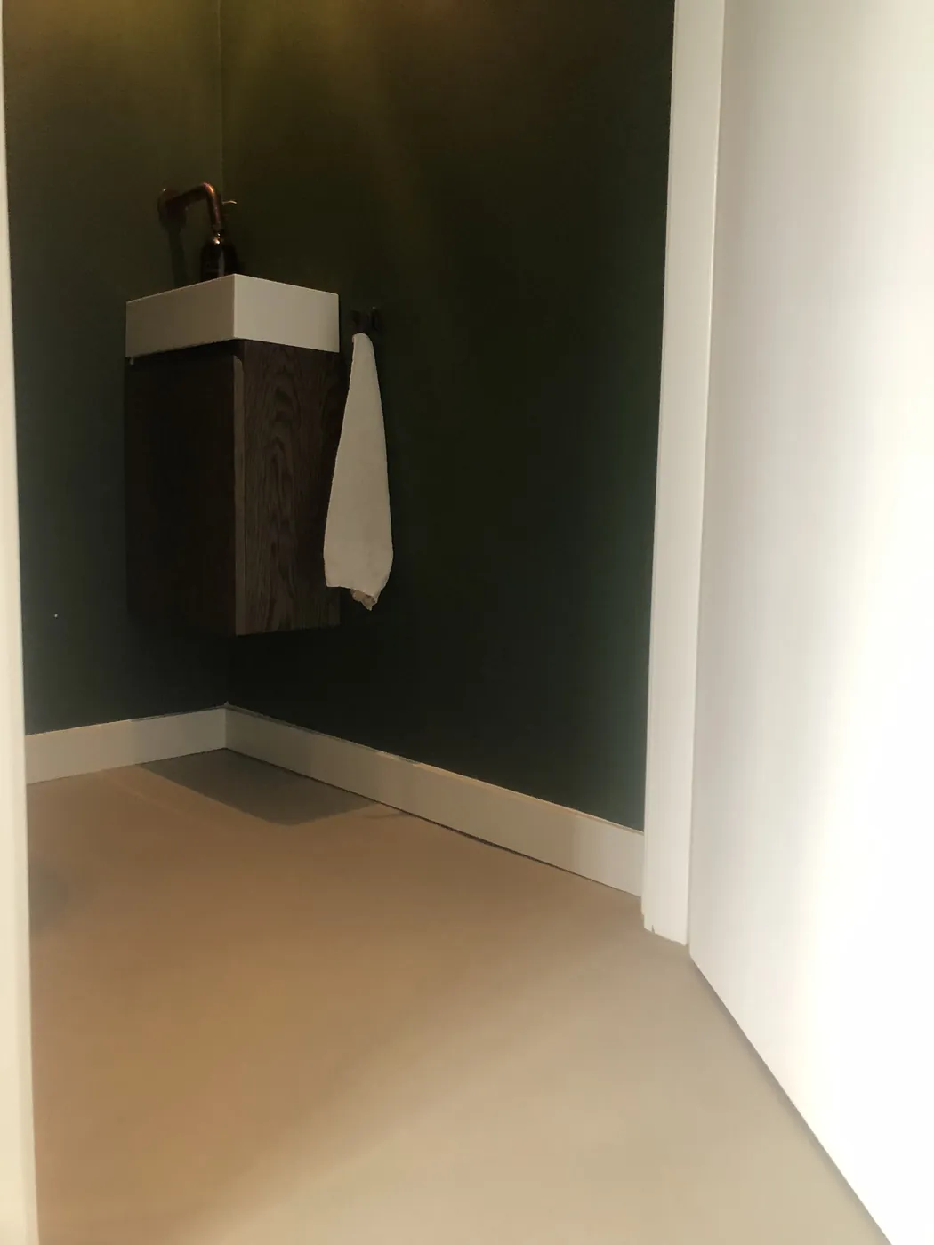Taupe gietvloer in toilet met zwevend wastafelmeubel