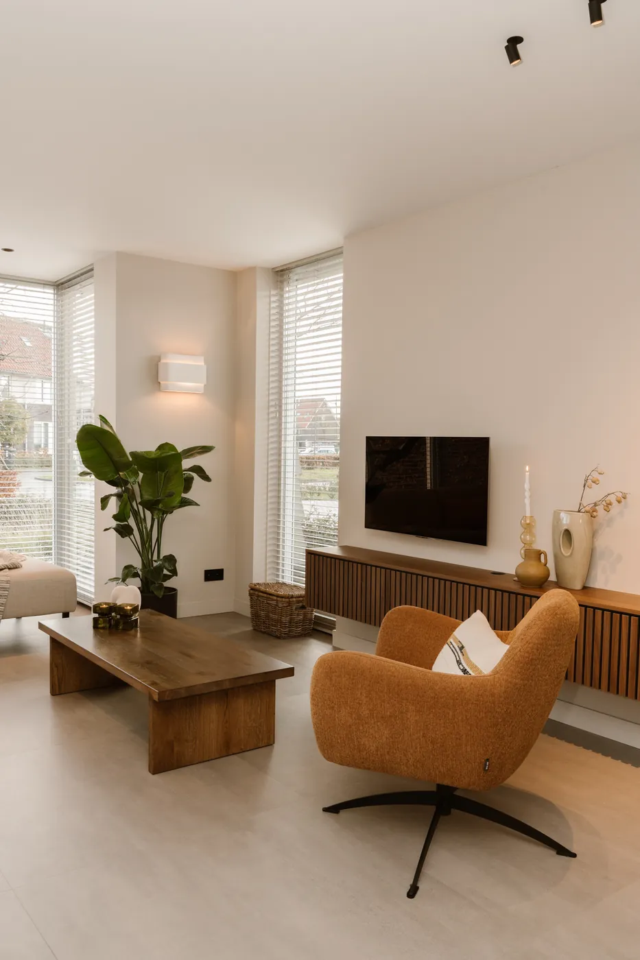 Betonlook pvc vloer met oranje fauteuil en tv-meubel