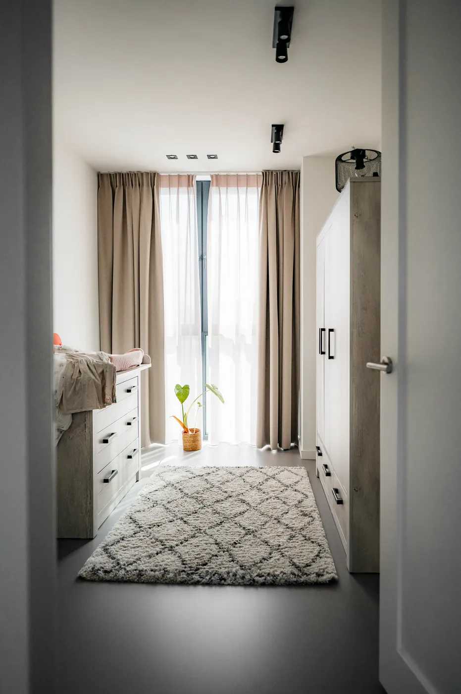 Smalle slaapkamer met antraciet gietvloer en vloerkleed