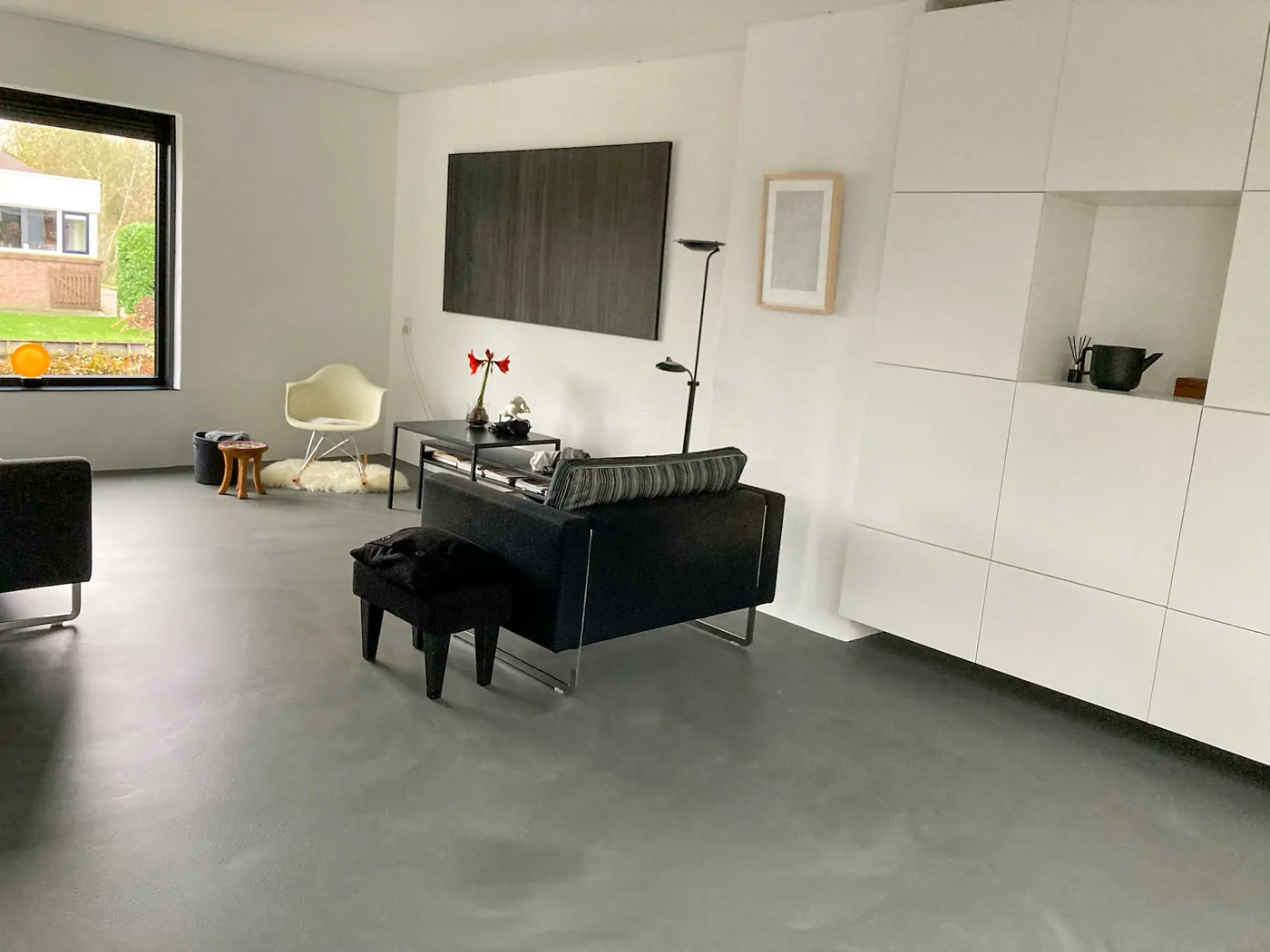 Donkergrijze antraciet gietvloer in woonkamer met zwarte bank