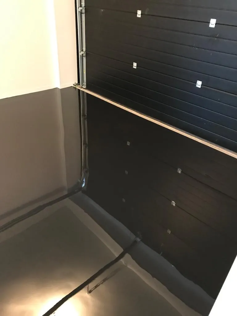 Donkergrijze epoxyvloer in garagebox met sectionaaldeur