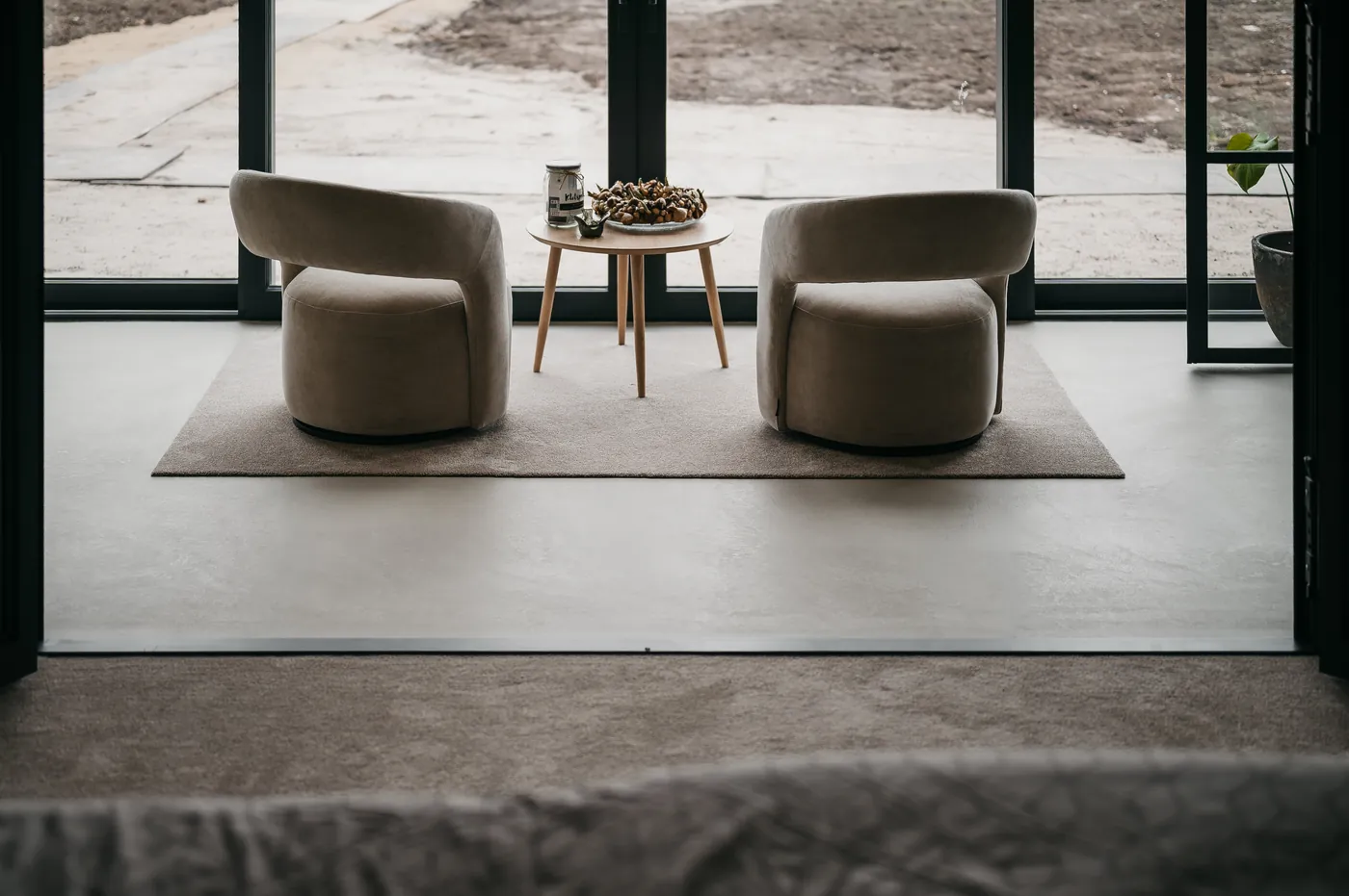 Grijze gietvloer in een loungehoek bij de tuinpui