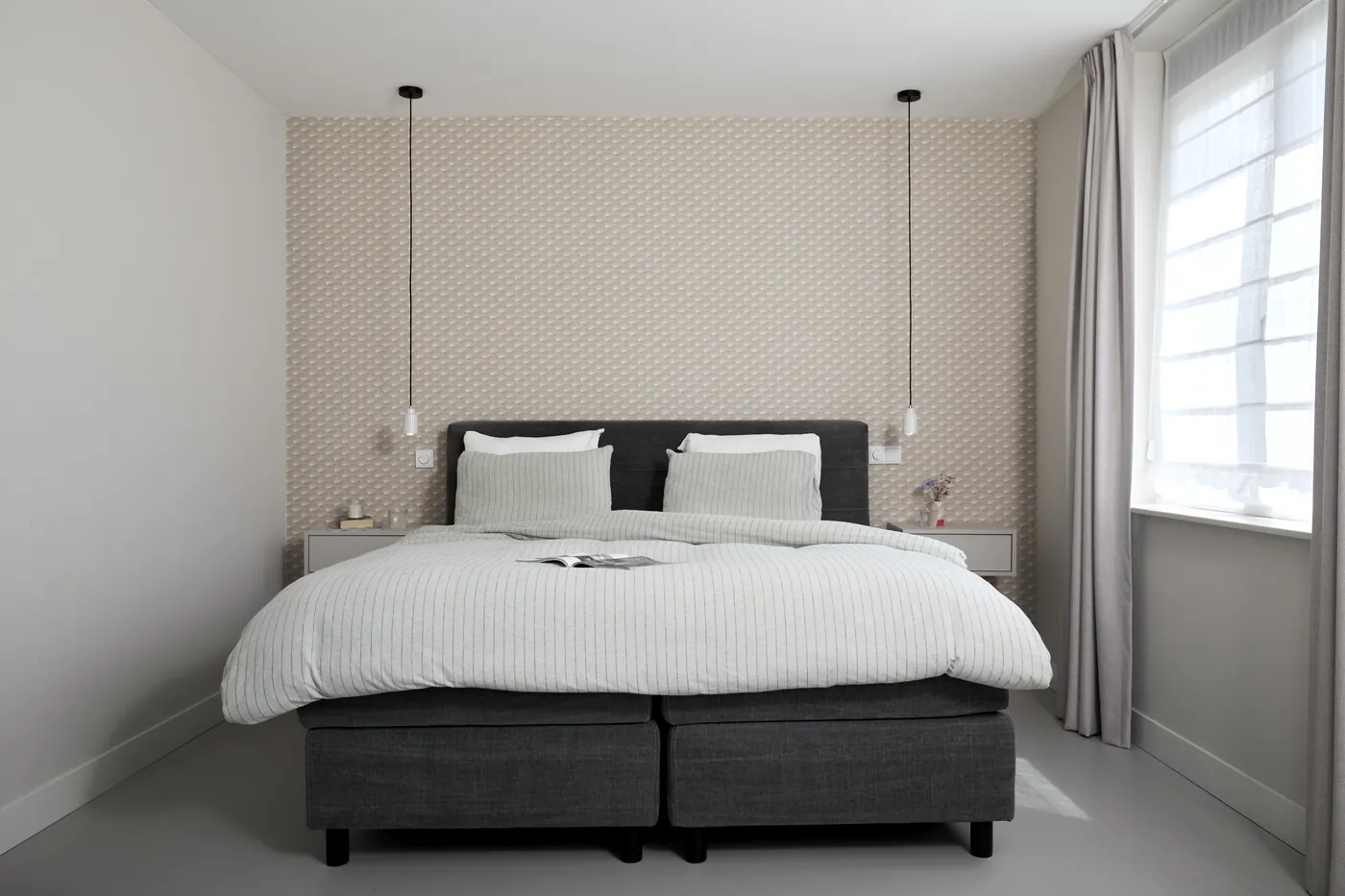 Lichtgrijze gietvloer bij een donkere boxspring