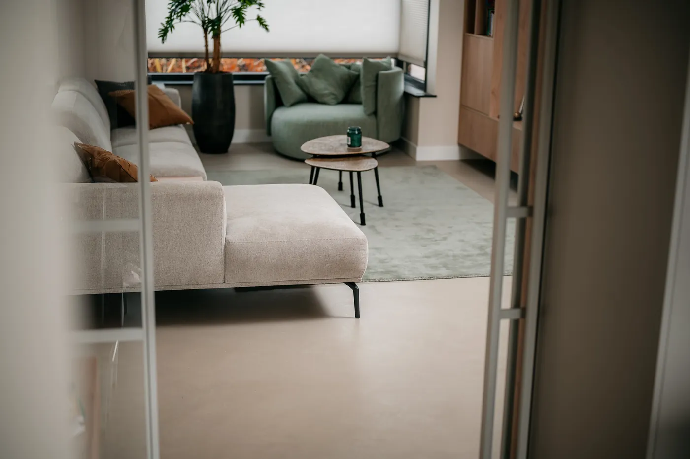 Woonkamer met beige bank en groene fauteuil