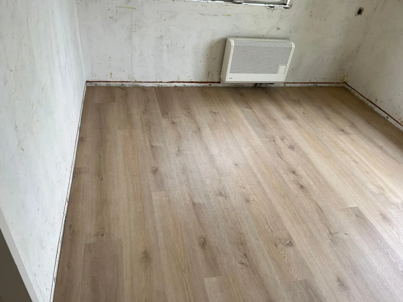 Lichte PVC vloer leggen in een lege ruimte