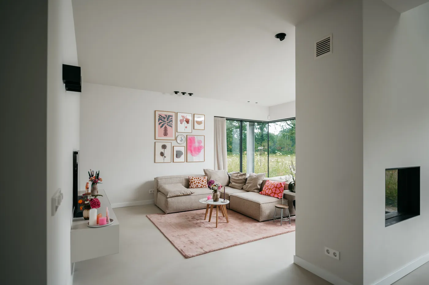 Hoekbank met roze vloerkleed en gallery wall